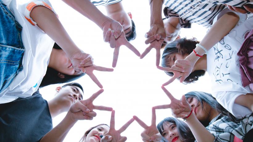 Eine Gruppe von Freunden steht im Kreis und formt mit den Händen einen Stern