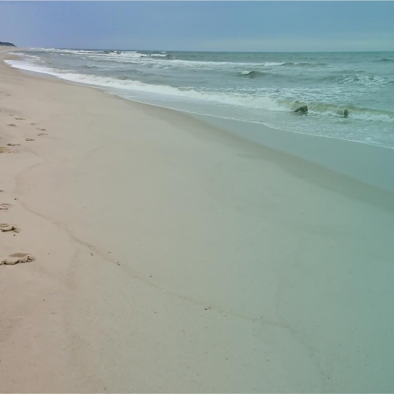 Sandstrand mit leichten Wellen rechts