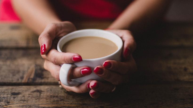 Frau fält Kaffeetasse in beiden Händen