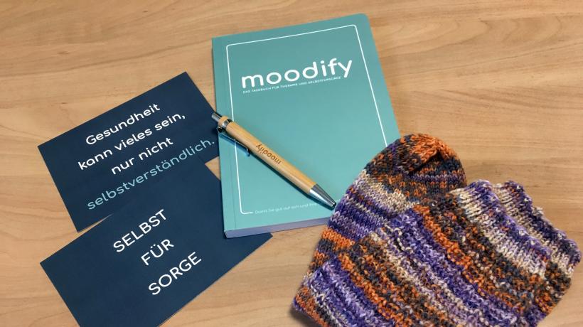 (Foto: Junfermann Verlag) Paketinhalt: 2 Postkarten, Socken, moodify-Tagebuch, Kugelschreiber