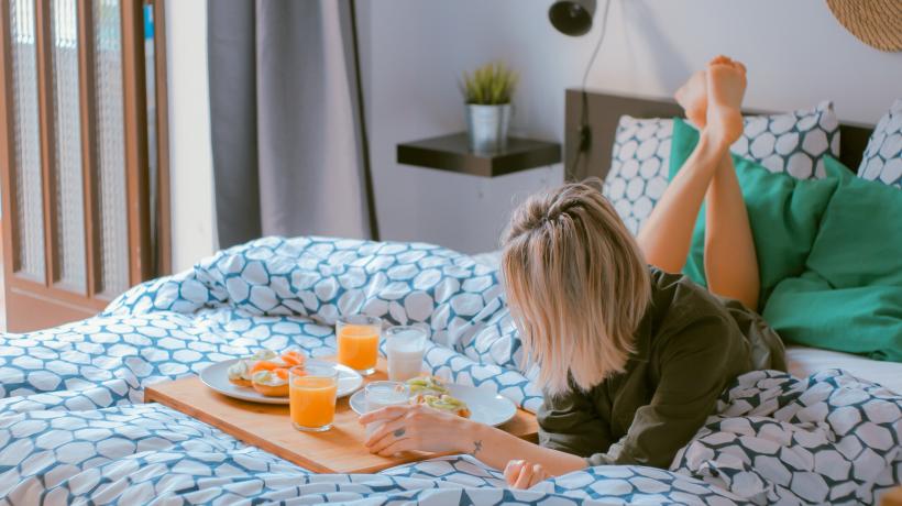 Frau lieg auf Bett mit Frühstückstablett