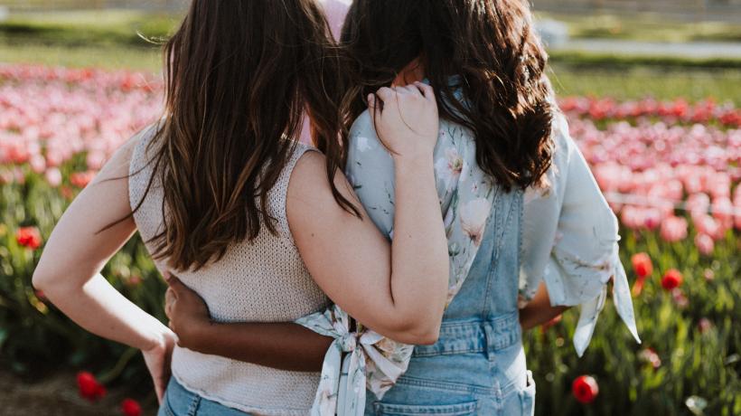 Frauen umarmen sich vor Tulpenfeld