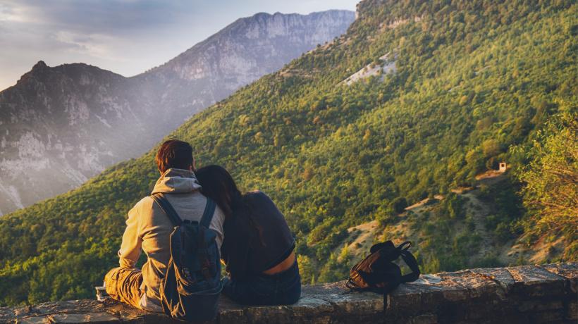 Auf Gleichklang kannst du deine Suche so gestalten, dass du Menschen findest, die zu deinem Lebensstil passen. (Foto: Mali Maeder - pexels.com) Zwei Menschen sitzen auf Steinmauer mit dem Rücken zum Fotografen. Überblicken Bergkette. Einer hat den Kopf auf die Schulter des anderen gelegt.