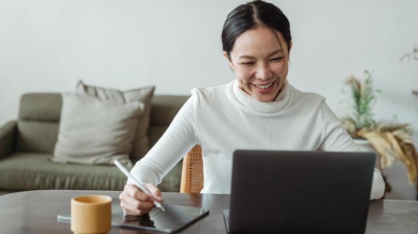 Frau arbeitet fröhlich am Laptop.
