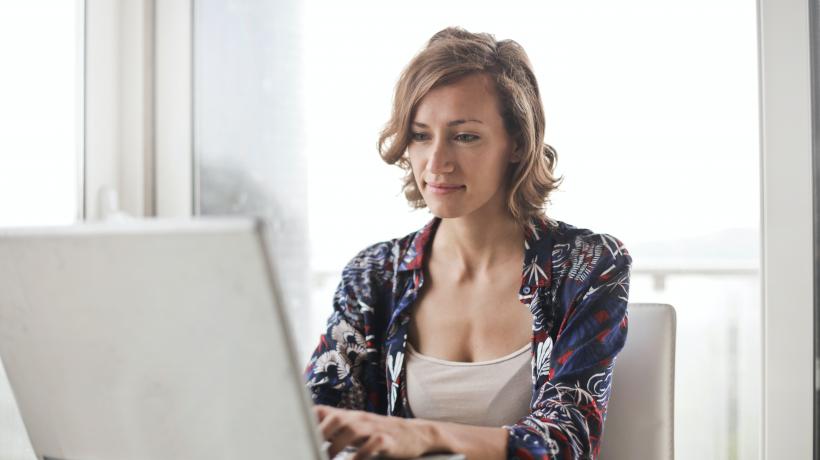 (Foto: Andrea Piacquadio – Pexels.com) Frau sitzt am Tisch vor einem aufgeklappten Laptop.