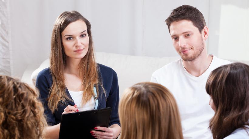 (Foto: Fotolia.com) Vier junge Frauen und ein Mann besprechen sich in der Gruppe, während eine Frau Notizen macht.