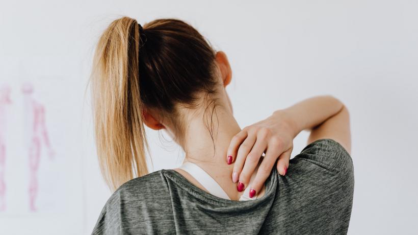 Frau hält aufgrund von Schmerzen ihre Hand an den Rücken