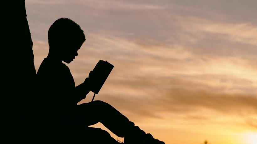 Lesendes Kind im Sonnenuntergang