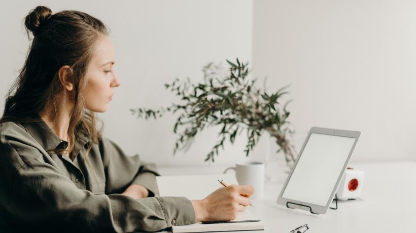 Foto:Cottonbro – Pexels.com Junge Frau sitzt am Schreibtisch und arbeitet mit dem iPad.