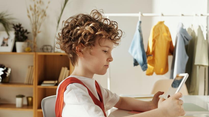 Foto: Julia Cameron – Pexels.com Kind sitzt am Schreibtisch und schaut sich etwas auf einem iPad an.