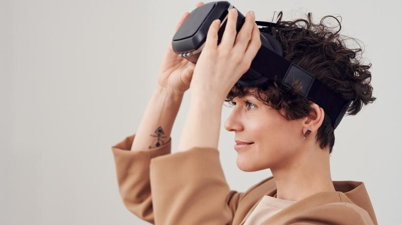 Frau setzt sich eine VR-Brille auf.