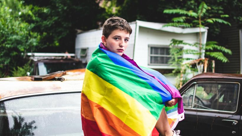 Junge in einer Regenbogenflagge auf einem Auto