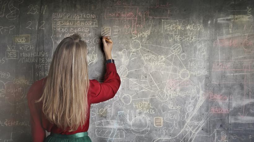 Frau schreibt Formeln an eine Tafel