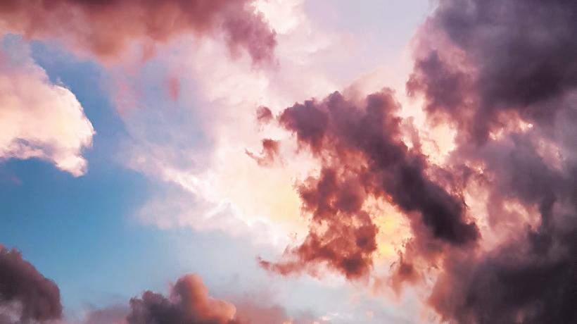 (Foto: eberhard grossgasteiger – pexels.com) Im Hintergrund ist der blaue Himmel zu sehen, davor sind helle und dunkle Wolken in verschiedenen gelb-roten Farbtönen zu sehen.