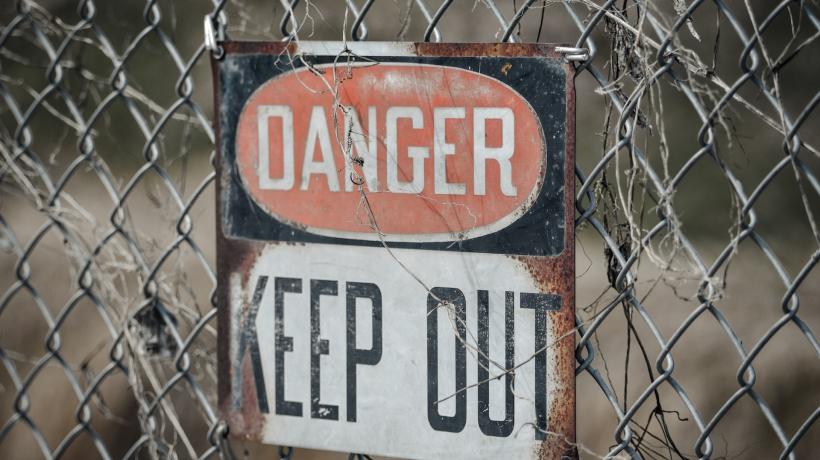 Schild an einem Zaun mit der Aufschrift: Danger. Keep out.