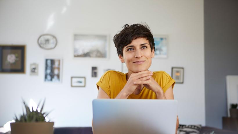 Foto: gettyimages Eine Frau mit kurzen Haaren und freundlichem Gesichtsausdruck sitzt am Schreibtisch vor ihrem Laptop.