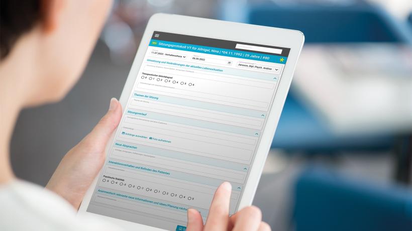 Foto: bloomicon – stock.adobe.com Eine Person hält ein Tablet in den Händen, auf dessen Bildschirm ein Sitzungsprotokoll zu sehen ist.