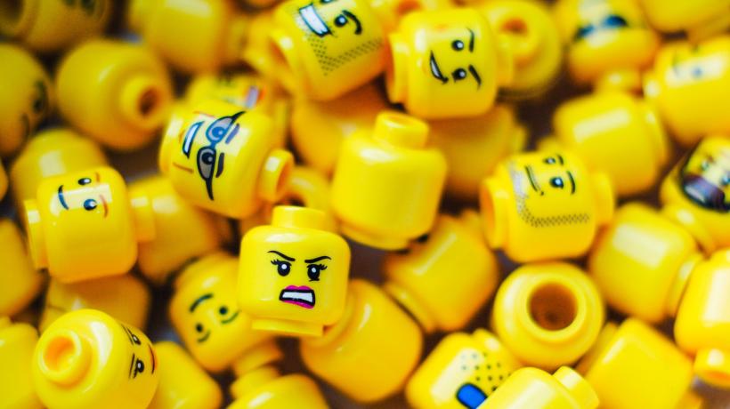 Viele Köpfe von Lego-Figuren mit unterschiedlichen Gesichtsausdrücken liegen auf einem Haufen.