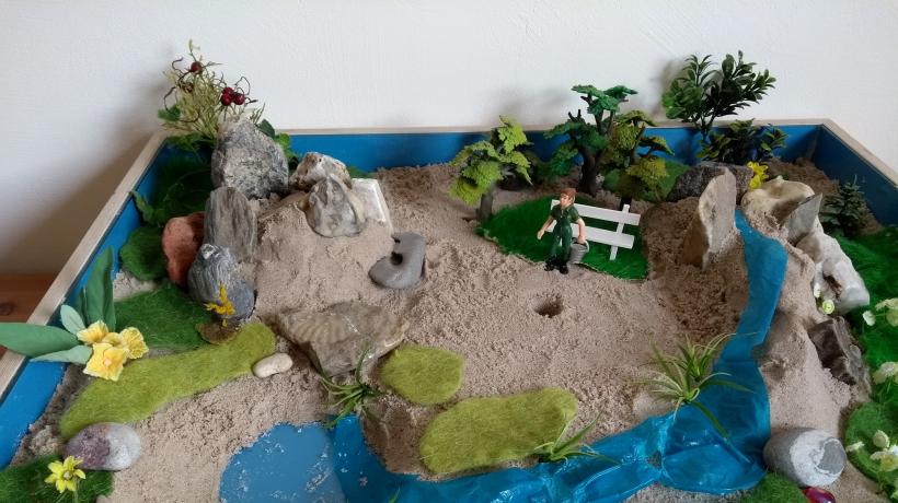 Eine gepflegte Gartenanlage als aufgebaute Szene in der Sandspieltherapie