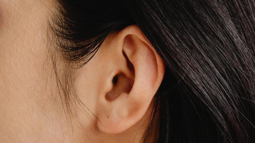 Nahaufnahme eines Ohres einer Frau mit schwarzen Haaren