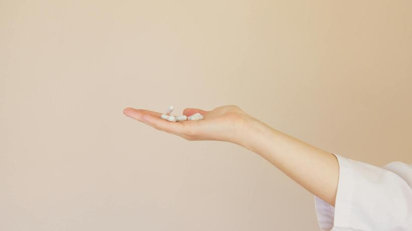 Auf einer Handfläche liegen Schmerzmittel in Tablettenform.
