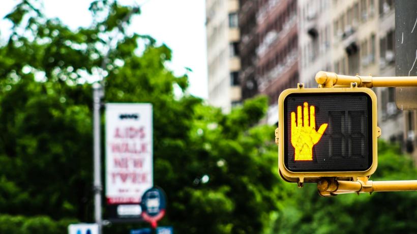 Eine Ampel mit gelbem Handsymbol, das STOP bedeutet.