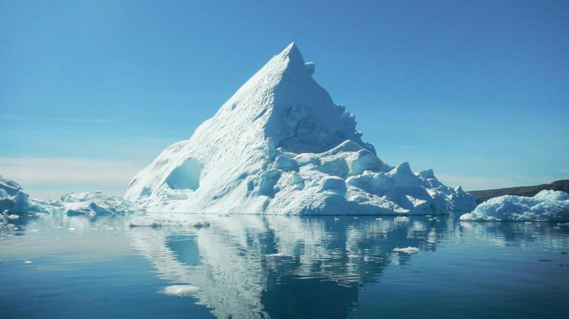 Foto: Jean-Christophe André – pexels.com Ein spitzer Eisberg im Meer umgeben von kleineren Eisschollen