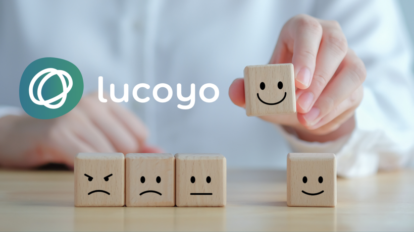 Foto: Wipada Wipawin - Canva Logo von Lucoyo, darunter fünf Steinchen mit aufgemalten Gesichtern. Der lachende Stein wird hochgehalten.