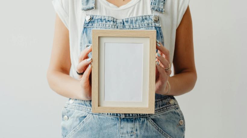 Foto: Kaboompics.com – pexels.com Eine Frau hält einen kleinen leeren Bilderrahmen auf dem Schoß