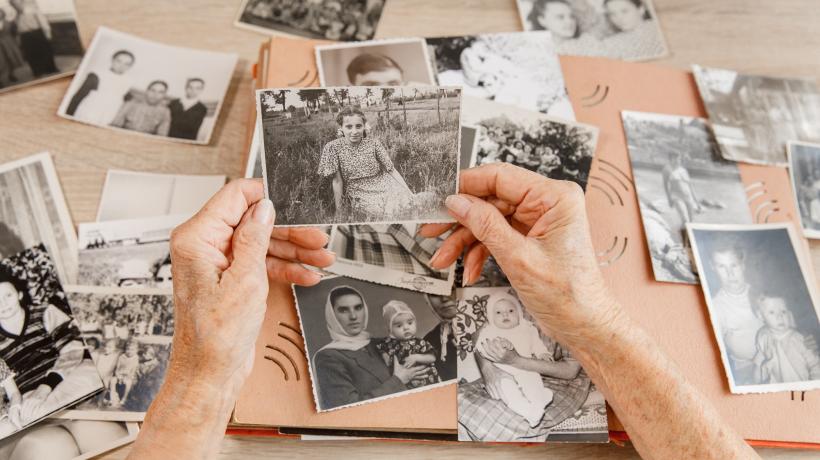 Foto: Татьяна Яблокова – stock.adobe.com Man sieht die Hände einer älteren Person, die sich alte Fotos anschaut.