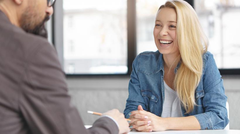 Foto: wayhomestudio – freepik.com Eine blonde Frau sitzt einem dunkelhaarigen Mann gegenüber. Zwischen ihnen liegen Texte auf dem Tisch.