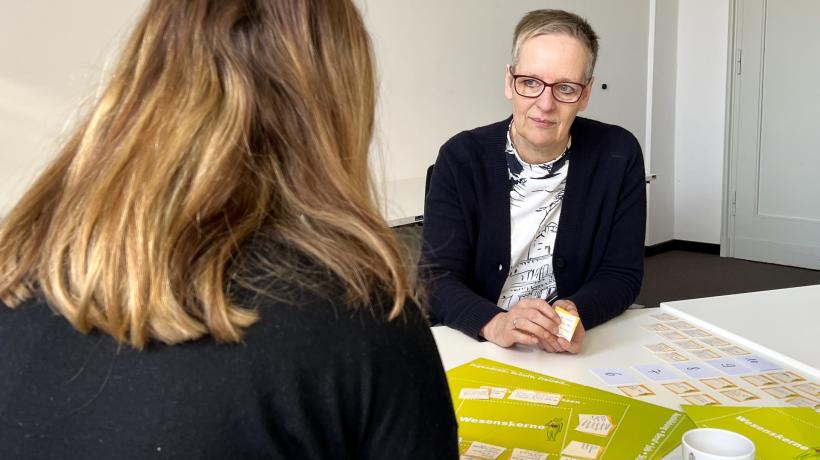 Zwei Frauen sitzen sich gegenüber, zwischen ihnen das Wesenskernspiel