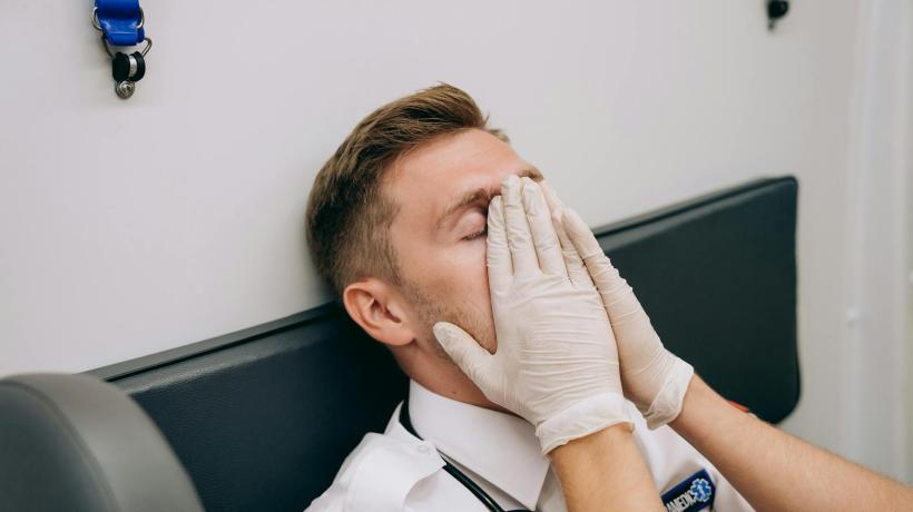 Foto: Mikhail Nilov – pexels.com Ein Mann mit Hygienehandschuhen legt sich müde die Hände aufs Gesicht.