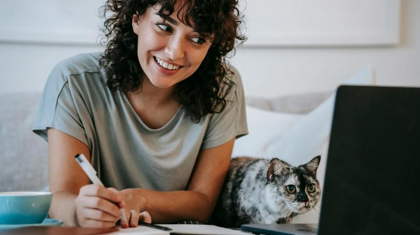 Foto: Sam Lion – pexels.com Eine junge Frau sitzt mit einem Notizblock am Laptop.