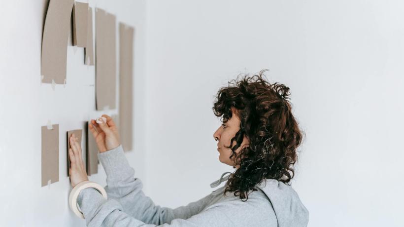 Eine Frau pinnt Papierkarten an die Wand.