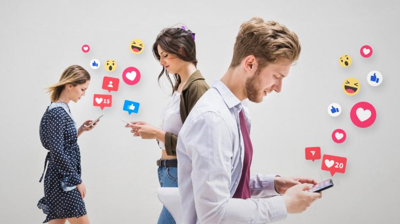 2 Frauen und ein Mann, die auf Ihre Smartphones schauen, von denen Emojis hochsteigen.