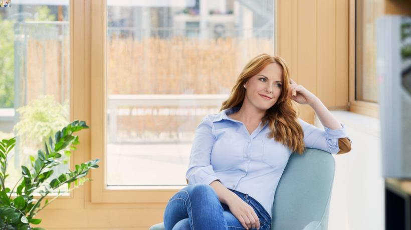 Eine Frau mit rötlichen Haaren sitzt auf einem Sofa