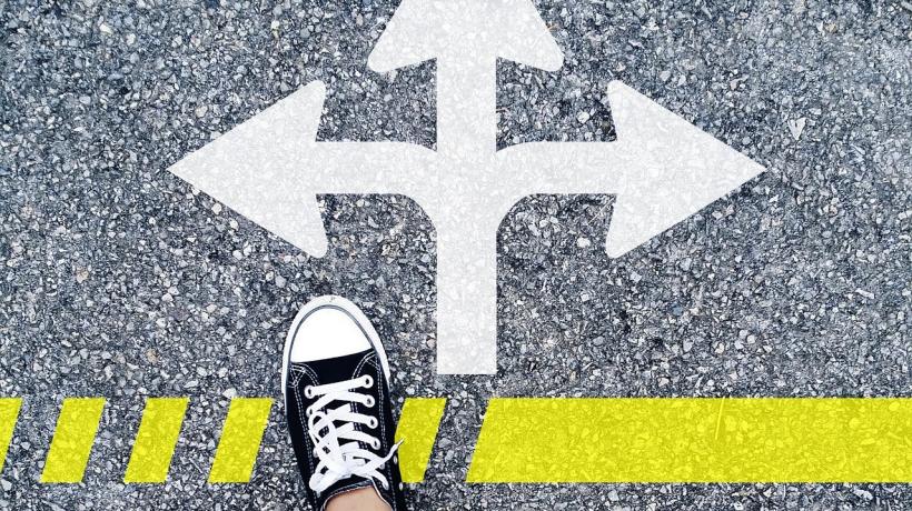 Ein Pfeil mit 3 Spitzen, davor zwei Füße in Turnschuhen.