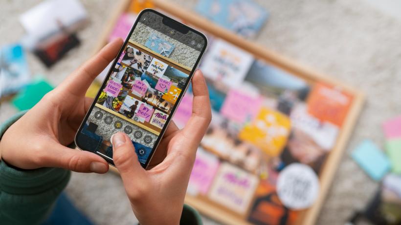 Man sieht von oben auf eine Person, die eine Collage mit dem Handy abfotografiert.