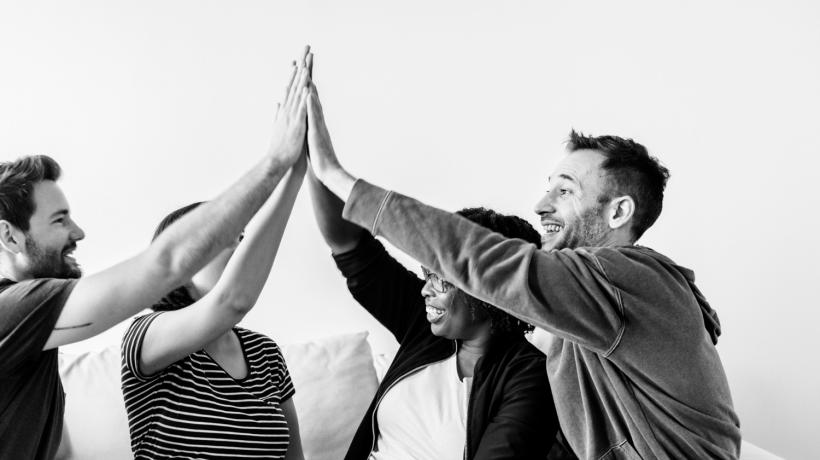 Vier junge Menschen geben sich High Five (Schwarz-Weiß-Foto)