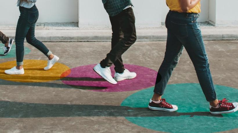 Man sieht vier Menschen von der Körpermitte abwärts, die auf bunten Kreisen laufen.