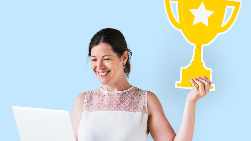 Eine Frau hält einen Papp-Pokal hoch.