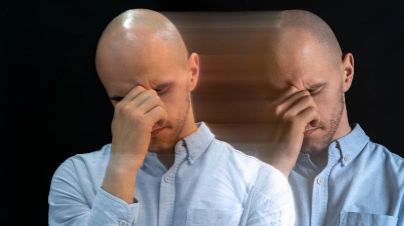 Ein Mann stützt sein Gesicht in die Hand, verwaschen ist ein Double von ihm zu sehen.