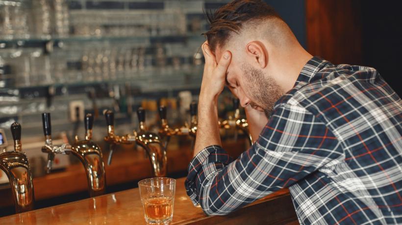 Ein Mann einer Bartheke, der den Kopf in die Hände stützt