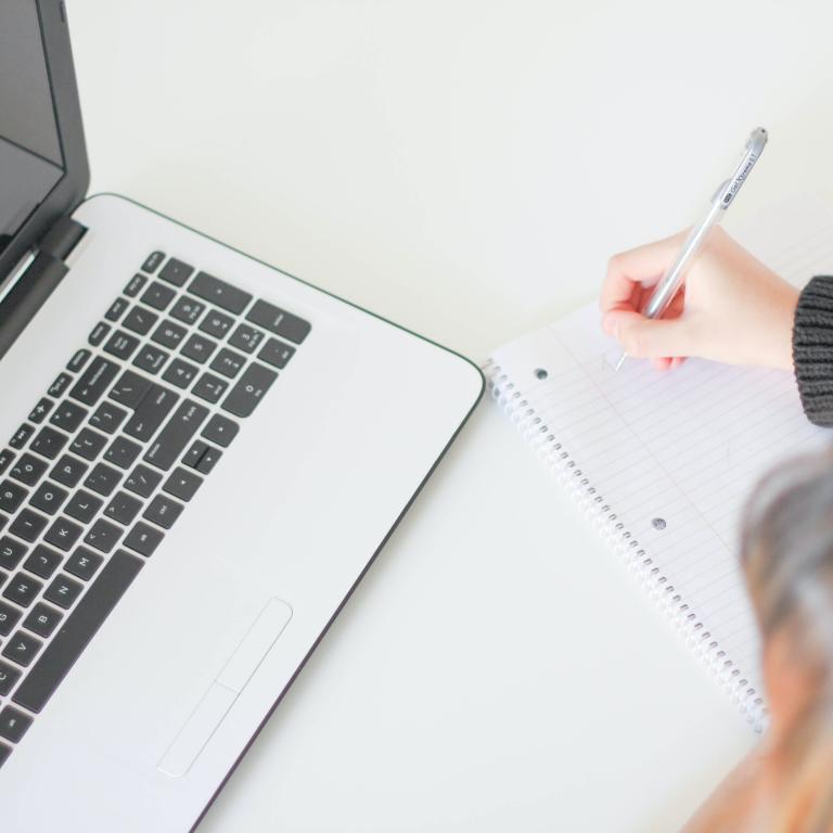 Foto: J. Kelly Brito - Unsplash.com Frau vor Laptop schreibt etwas auf.