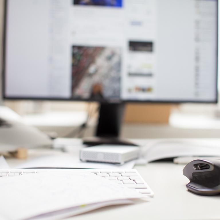 Foto: Taduuda - Unsplash.com Schreibtisch mit verschiedenen Unterlagen und Bildschirm im Hintergrund.