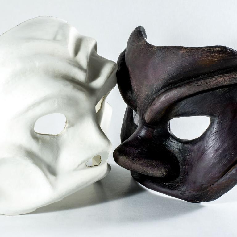 zwei Theatermasken, eine weiße, eine schwarze liegen nebeneinander