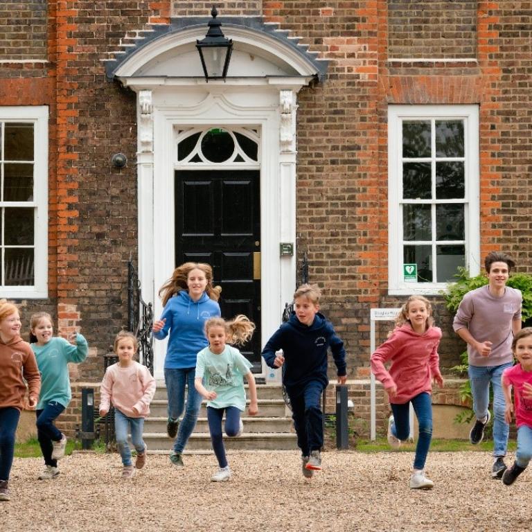 Foto: Deutsche Schule London Schülerinnen und Schüler laufen lachend auf die Kamera zu.
