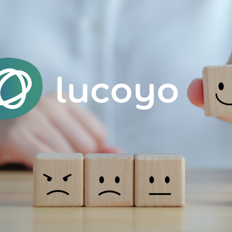 Logo von Lucoyo, darunter fünf Steinchen mit aufgemalten Gesichtern. Der lachende Stein wird hochgehalten.