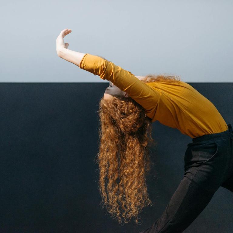 Eine Frau wird im Profil gezeigt, sie neigt den Oberkörper nachhinten, wie in einer Ballettpose.